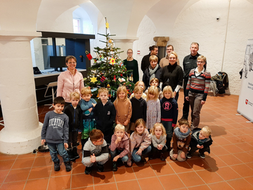 Kinder vom Kindergarten vorm geschmückten Tannenbaum