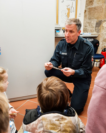Wachtmeister zeigt den Kindern Handschellen